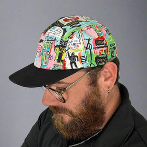 Person wearing a colorful cap with graphic designs on a gray background