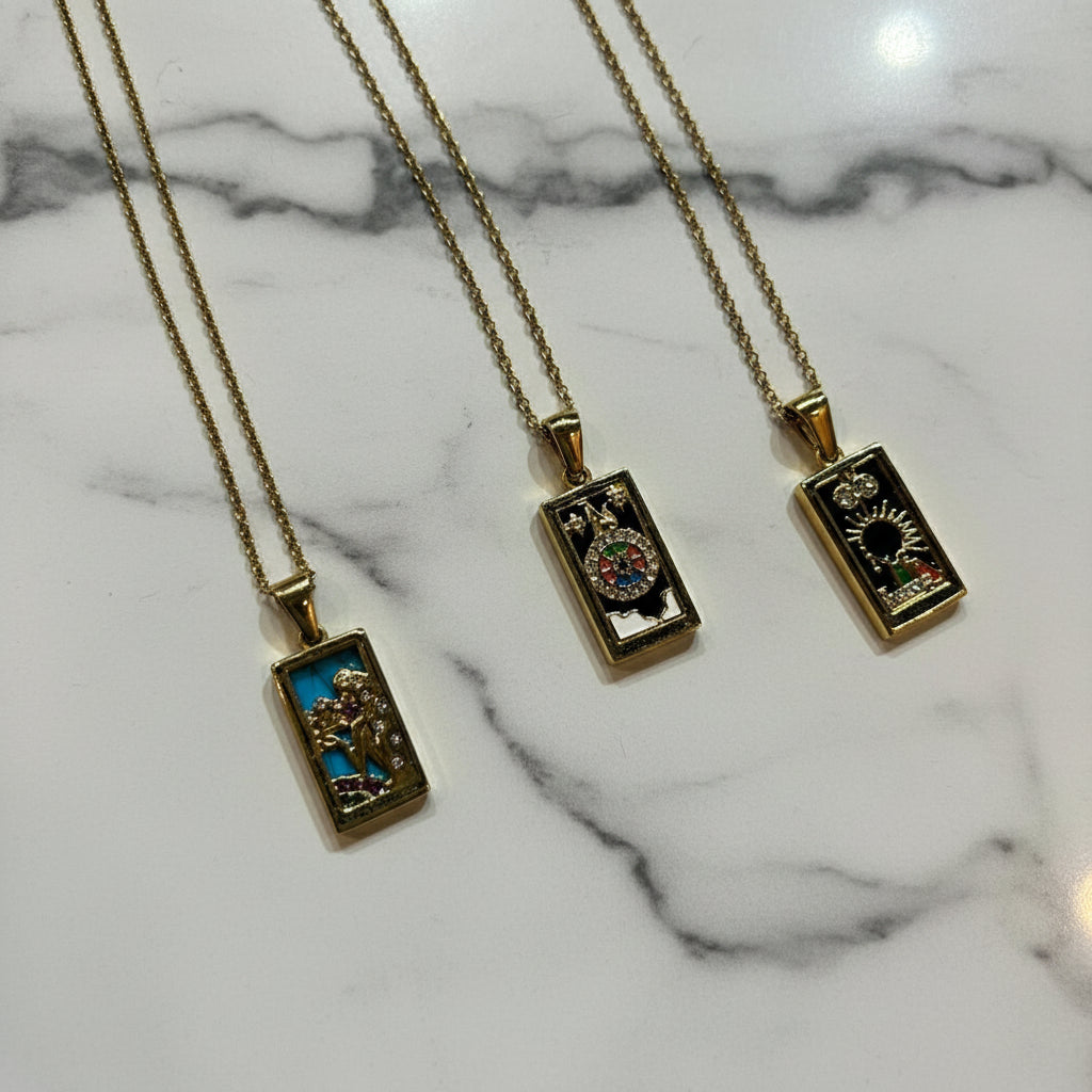 Three gold necklaces with rectangular pendants on a white background