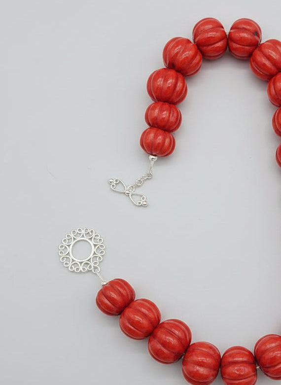 Red beaded necklace with a silver clasp on a light gray background