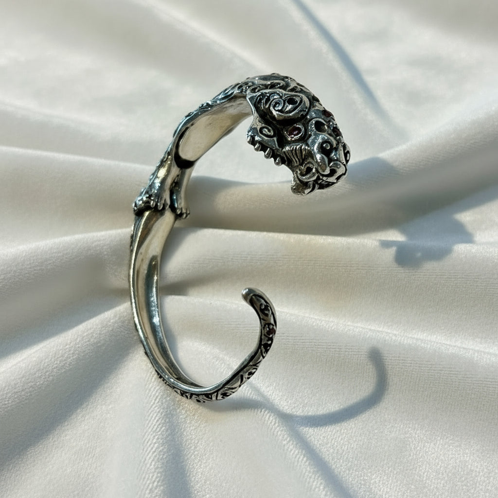 Silver bracelet with intricate design on a light background