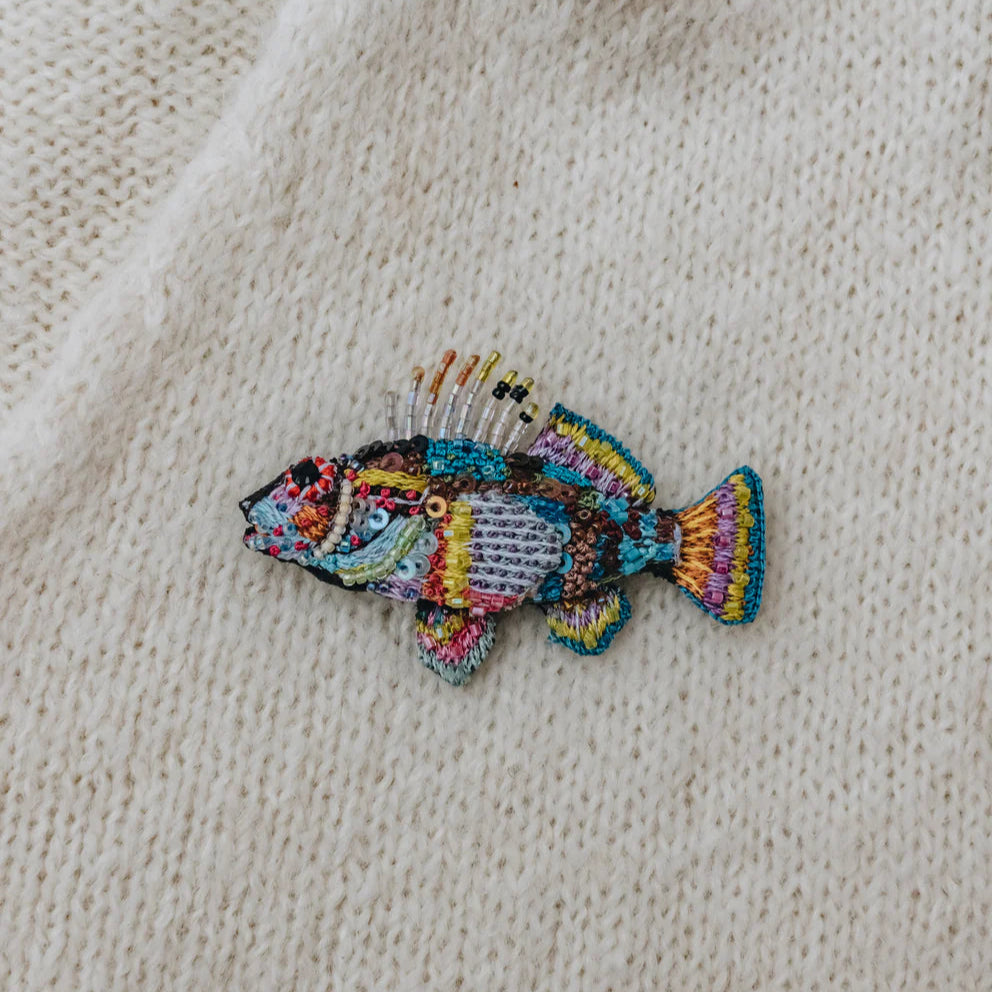 Colorful fish patch on a beige fabric background