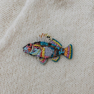 Colorful fish patch on a beige fabric background